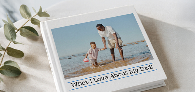 Closed photobook showing photos of a son and father on the cover that reads 'my dad is my superhero'.