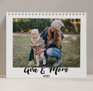 Closed calendar leaned against the wall showing photo of mom and daughter that reads 'Ava & Mom 2024'.