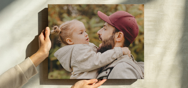 Woman hands placing an 11x9 canvas print on the wall of a photo showing a young girl with her dad during autumn.