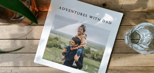 Closed photobook showing photos of a son and father on the cover that reads 'my dad is my superhero'.