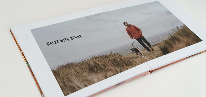 Open layflat photobook showing a photo of a couple on a mountain that stretches across the entire book.