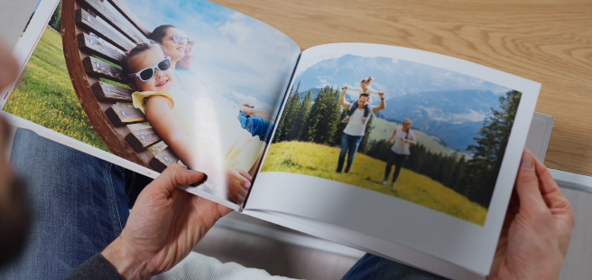 Woman holding an open photobook showing photos of friends celebrating the 4th of July.