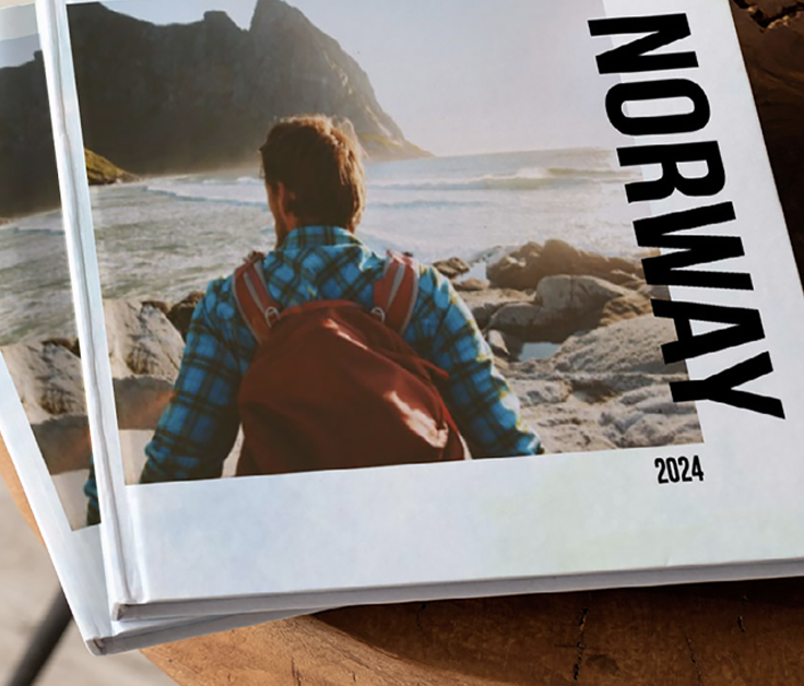 Two photobooks stack on top of each other with a photo of a man looking over the ocean on the front with the text Norway 2024'