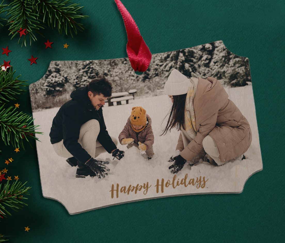 Ornament showing photo of young family playing in the snow that reads 'Happy Holidays'.