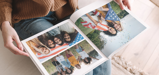 Woman holding an open photobook showing photos of friends celebrating the 4th of July.