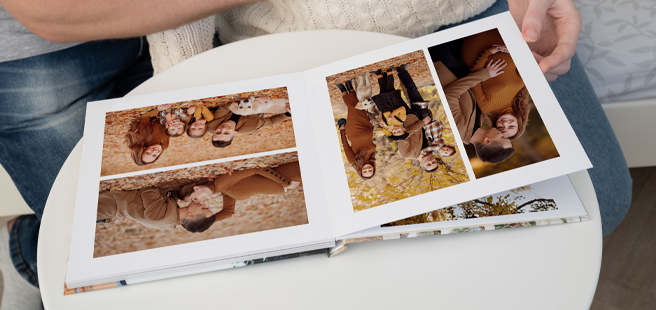 Pregnant couple flipping through their lay-flat photobook of their autumn family photoshoot.