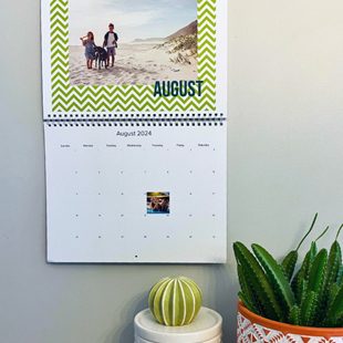 Open calendar hung up on the wall featuring a photo of two children and a dog with the text 'August' underneath